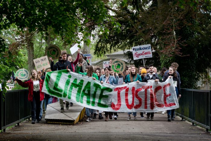A large group of young people hold a climate justice banner
