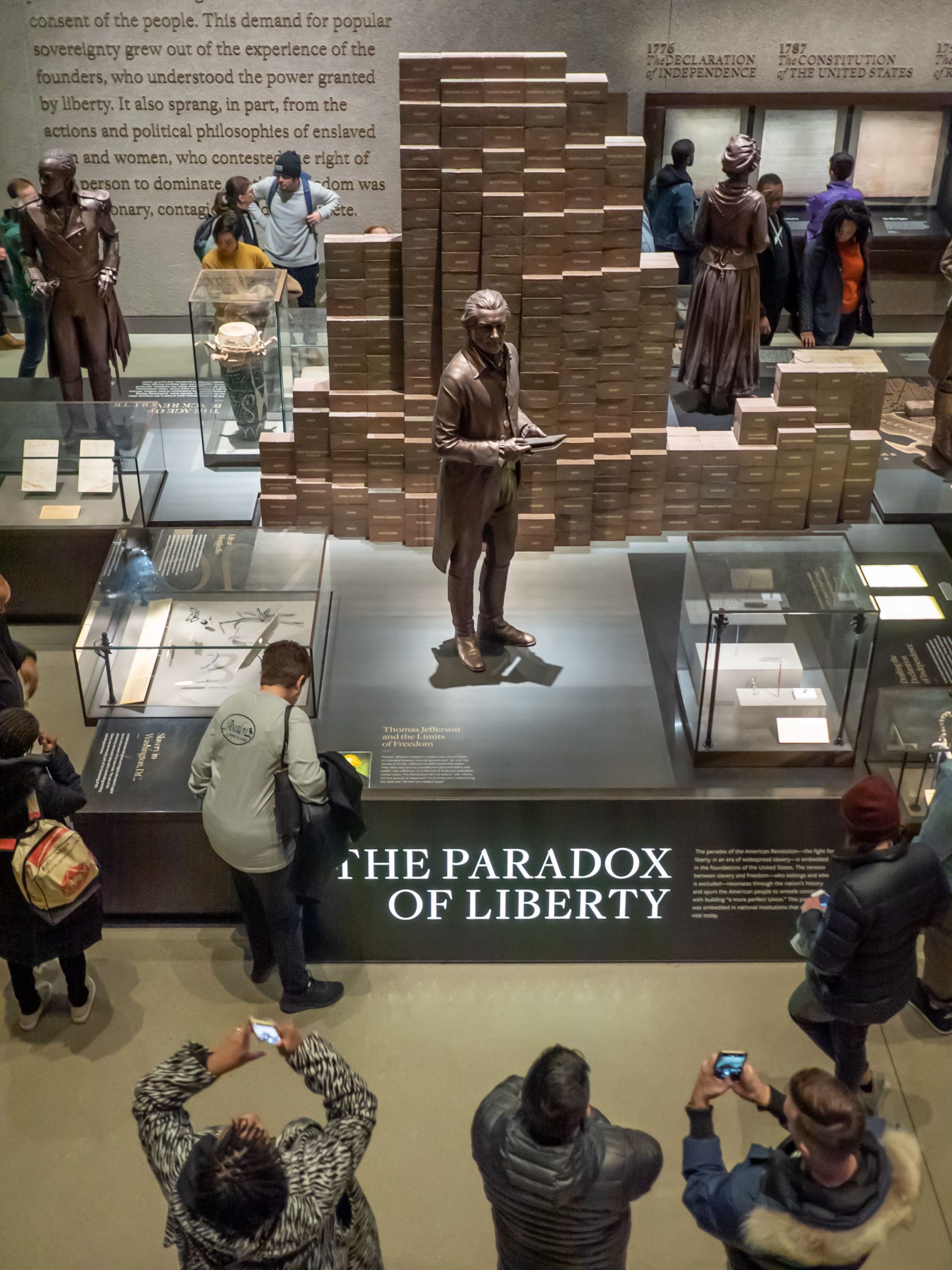 People looking at museum exhibit with statue of Thomas Jefferson at center