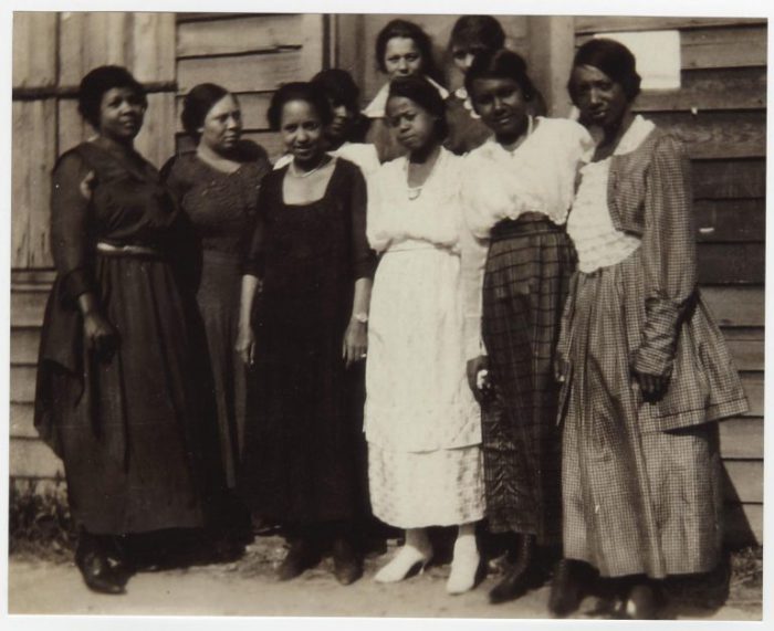 Black and white photo of a group of African American women standing in front of a building