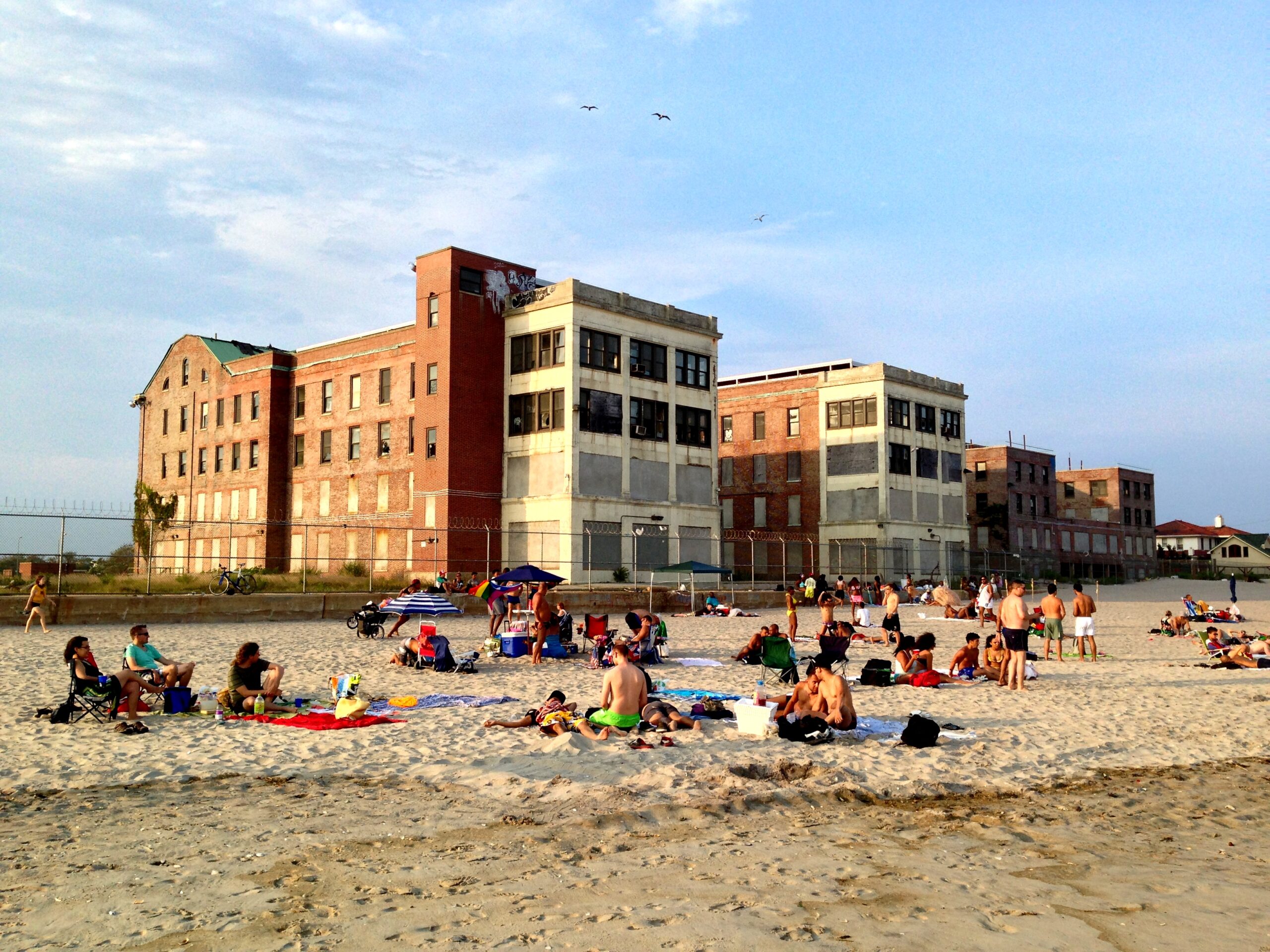 A color photograph of a beach with a large building in the background